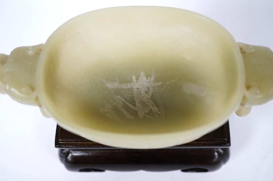 A Chinese archaistic pale green bowenite jade twin handled cup on stand, cup 11.5cm wide. Condition - cup good, stand good
